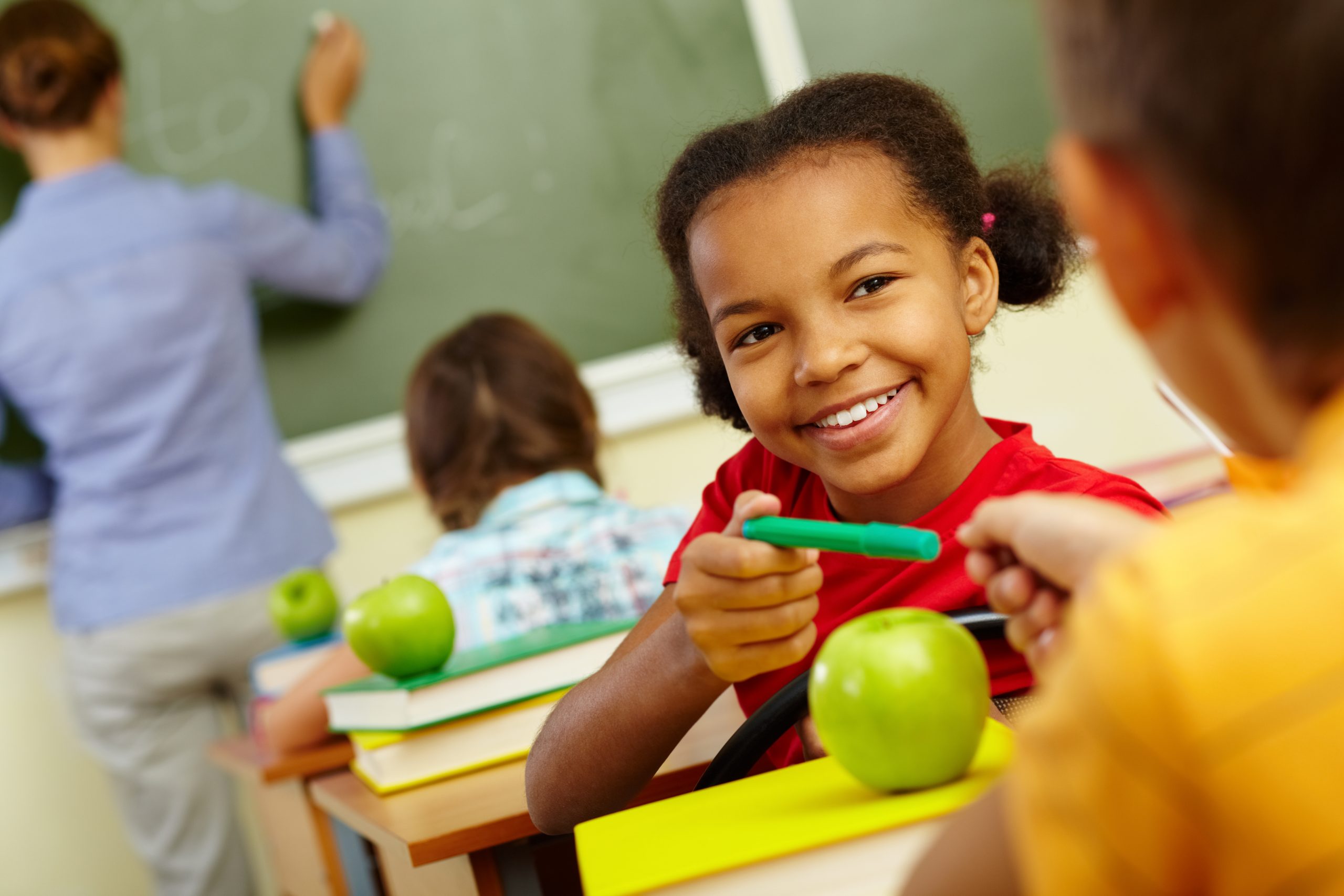 Portrait of cute girl giving crayon to classmate at lesson